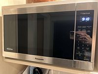 Front view of Panasonic inverter microwave showing stainless steel finish, digital control panel, model number label