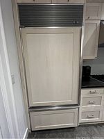 Closed front view showing panel-ready installation with custom wood panels and stainless steel grille.