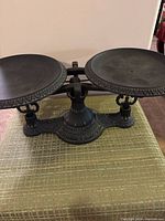 Full front view of the antique cast iron balance scale showing both round plates and decorative central base.