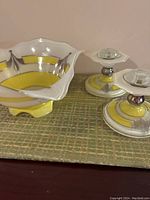 Photo of large fruit bowl and two matching candle holders on a green textured surface