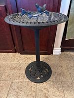 Full view of the cast metal bird bath showing round basin, decorative bird figures, and ornate base