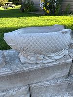 Side view of the concrete fish-shaped planter showing detailed fish scale texture and decorative base.