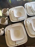 Set of dishes and mugs showing arrangement of large plates, lunch plates, bowls, and mugs with cherry blossom design.