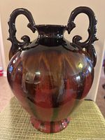 Photo of large rounded double handle vase with dark brown, black, and reddish glossy glaze.