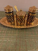 Front view of gold plated salt and pepper shakers and condiment pot with blue cobalt glass inserts on ornate tray