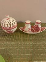Porcelain salt and pepper shakers on matching tray with a covered lattice dome dish nearby