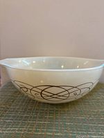 Front view of large white Pyrex bowl showing brown swirl decorative design around the exterior.