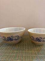 Two beige Pyrex mixing bowls side by side showing navy blue floral design.