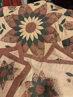 Full view of quilt showing scalloped edge, large sunburst floral applique with petals in checked and floral fabric patches.