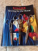 Front cover of Singer 'Sewing for the Home' reference book with three Singer scissors laid across it.