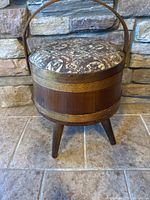 Full view of vintage wooden sewing basket on tripod legs with handle and upholstered lid.