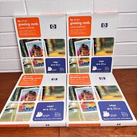 Two sets of HP photo greeting card kits standing vertically side by side showing front packaging in detail.