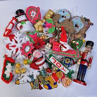 Top view of assortment of Christmas ornaments including felt, wood, and glitter figures such as Santa, snowman, candy cane stocking, and nutcracker