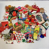 Photo showing a wide assortment of vintage and handmade Christmas ornaments including fabric, crocheted, wooden, and cardboard pieces with holiday themes