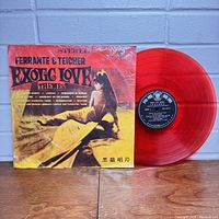 Photo showing front cover of the album sleeve with the red vinyl record partially pulled out, displaying the red colored vinyl and black/white center label with Japanese text.