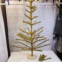 Full front view of assembled gold tinsel tree on round wood base