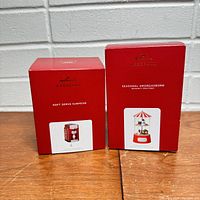Two red Hallmark Keepsake ornament boxes, one labeled Soft Serve Surprise showing an image of a soft serve ice cream machine ornament, and the other labeled Seasonal Smorgasbord with an image of a carnival food stand ornament.