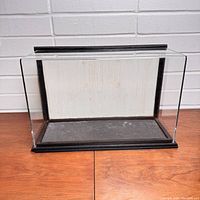 Front view of the rectangular glass display case with black frame base and back panel shown.