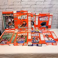 Six vintage 1996 Wheaties cereal boxes displayed unfolded and flat on a white surface in front of a brick wall, showing front, back, and side panels with vibrant sports-themed artwork and athlete images.