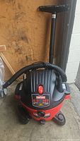 Full view of red and black Craftsman shop vac with hose and handle visible.