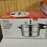 Box showing 7 liter pressure cooker with handles and lid including vent