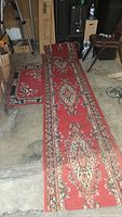 Photo of a red floral hall runner alongside a matching smaller area rug placed on a garage floor.