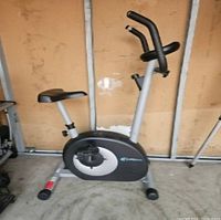 Side view of the stationary exercise bike showing its frame, seat, pedals, and handlebar design.