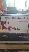 Box front showing KitchenAid Metal Food Grinder attachment with images of parts and food items.