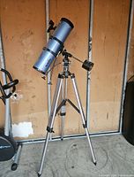 Full view of Sky Watcher telescope mounted on adjustable tripod stand in garage setting.