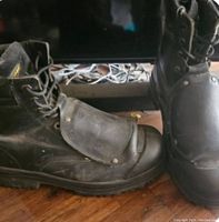 Pair of black Viper welding boots on wooden floor, showing front and side views including protective toe flap and laces.