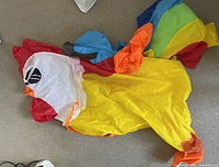 Photo showing the full deflated inflatable parrot costume laid flat, displaying the bright multicolor sections and bird face details.