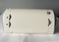 Front top view of white Cricut cutting machine showing power button and front latches