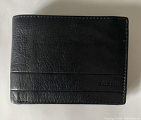 Front side of the black leather Fossil wallet showing the embossed FOSSIL logo and stitched detailing.