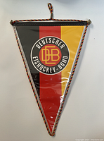 Triangular decorative pennant with black, red, and gold stripes and Deutscher Eishockey Bund emblem in center.
