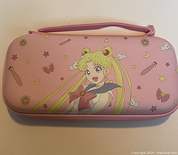 Exterior of pink Nintendo Switch case with Sailor Moon character artwork and decorative icons.