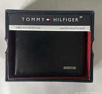 Front view of wallet in original Tommy Hilfiger box showing black leather and logo