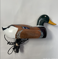 Side view of the wooden mallard duck phone showing painted details and the corded handset portion.