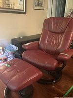 Red leather swivel recliner chair with matching ottoman shown together from front view