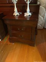 Front view showing two lower drawers, fluted column detailing, brass drop handles and bracket feet.