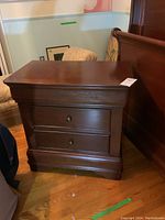 Front and right side view of dark brown wood nightstand with three drawers