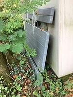 Table sections leaning against wall outdoors, resin top panels taped
