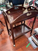 Angle view of the tea cart showing the removable top tray with handles and raised edges, top panel divided into sections, and brass hinge detail.