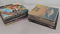 Two stacks of assorted vinyl record albums, showcasing a variety of colorful album covers and worn sleeves.