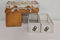 Longaberger basket with fabric liner and two linen storage bins side by side