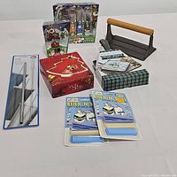 Full lot showing meat press, holiday spreaders, cast iron kit, glass dish, and packaged food savers