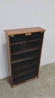 Front view of wooden media cabinet with closed glass doors and brass hinges.