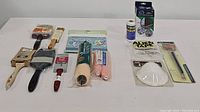 Full lot contents arranged on white surface showing variety of brushes, roller covers, masks, and accessories.