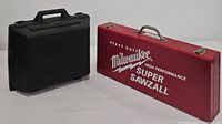 Red metal Milwaukee Super Sawzall carrying case beside a black plastic Craftsman carrying case on a white surface