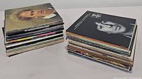 Two stacks of used vinyl record albums with visible spines showing artist names and album titles