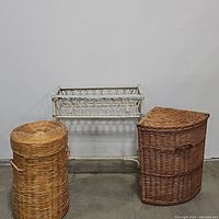 Lot photo showing three wicker baskets: a round lidded basket, a corner lidded basket, and a white wicker planter stand